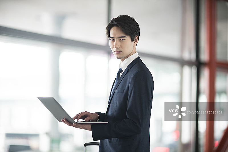 年轻商务男士在机场候机室使用笔记本电脑图片素材