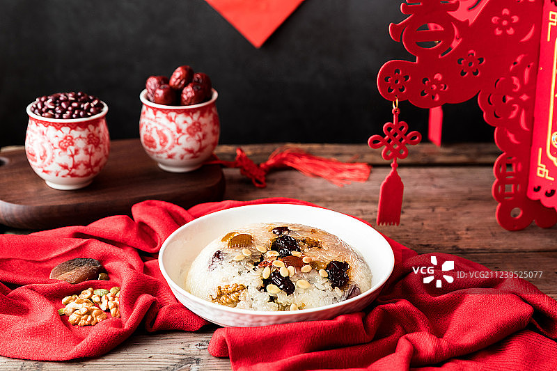 木桌上的放着中国传统美食八宝饭红豆红枣和春节挂饰图片素材