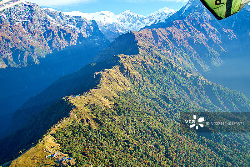 喜马拉雅山脉尼泊尔背景下的超轻型飞机、树木和雪山图片素材