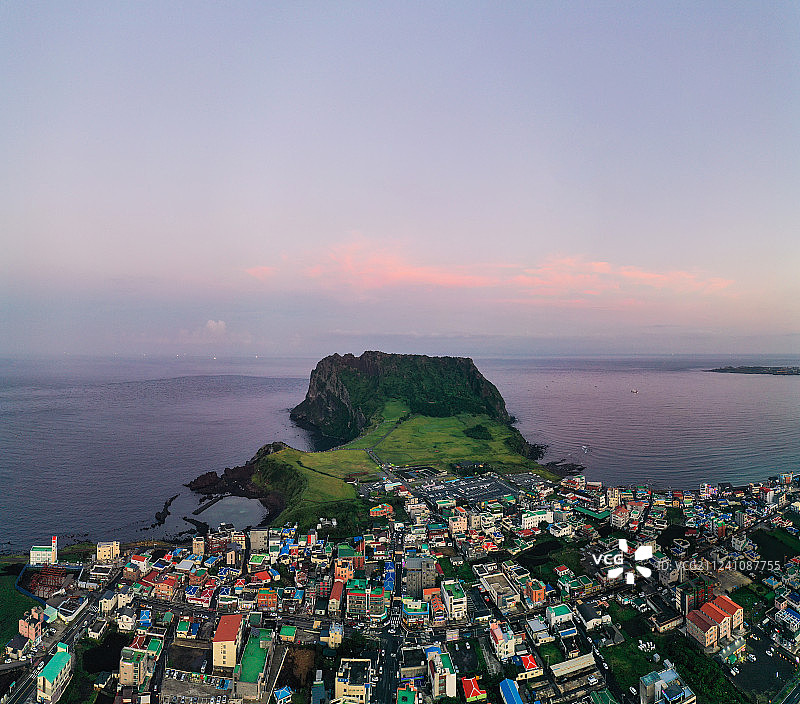 航拍的韩国济州岛旅游风光景观—彩色房子小镇前的城山日出峰图片素材