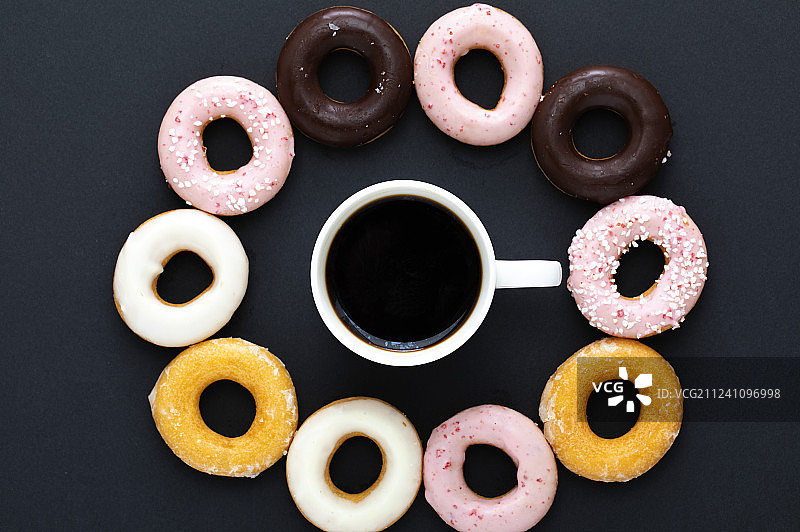 咖啡杯及甜甜圈在黑背景颜色上图片素材
