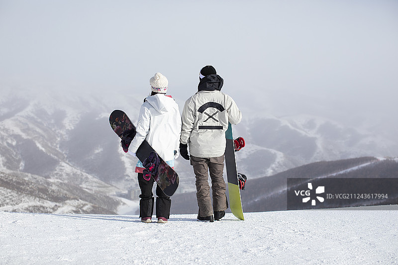 年轻情侣在滑雪场眺望远方图片素材