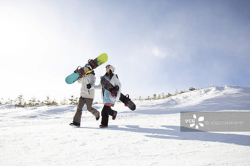 快乐的年轻情侣在雪地上奔跑图片素材