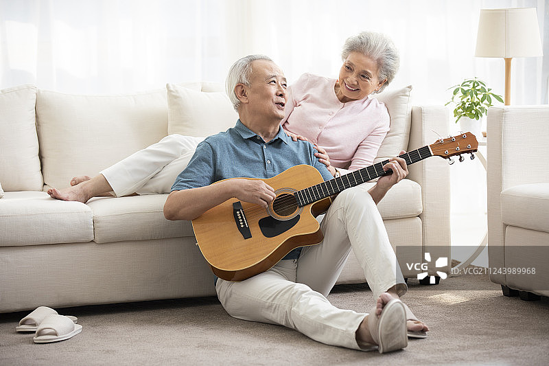 快乐的老年夫妇在客厅弹吉他图片素材