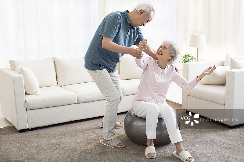 快乐的老年女士在客厅健身图片素材
