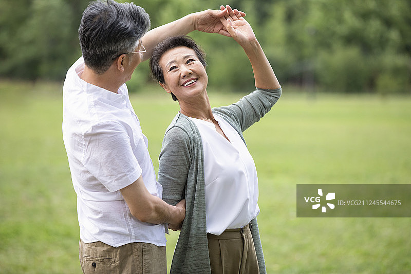 快乐老年夫妇在草地上跳舞图片素材