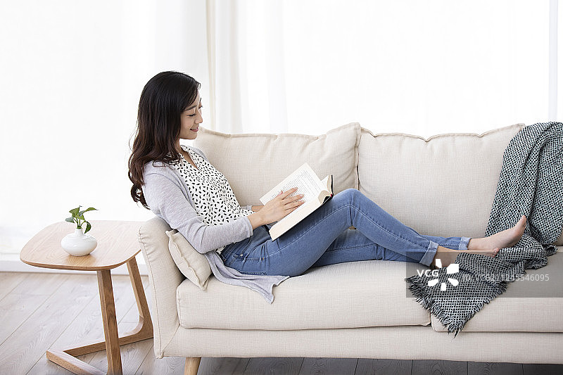快乐的年轻女士在家看书图片素材