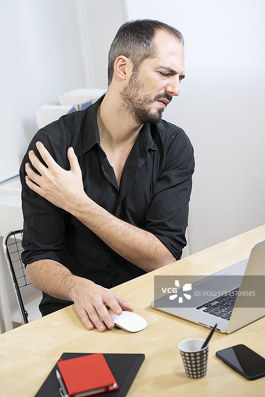 男人在办公桌前，肩膀疼痛图片素材