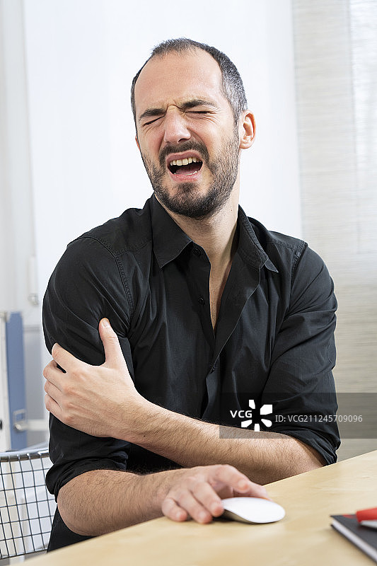 男人在办公桌前，肩膀疼痛图片素材