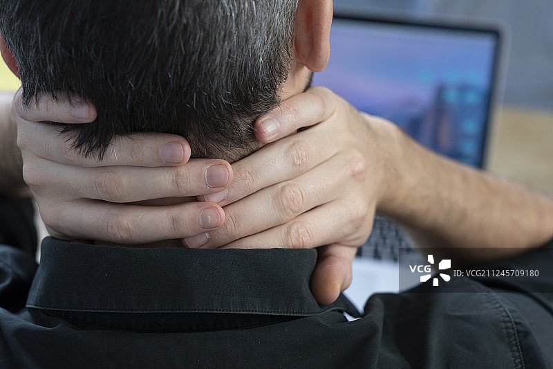男子在办公桌前感到颈部疼痛图片素材