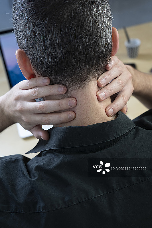 男子在办公桌前感到颈部疼痛图片素材