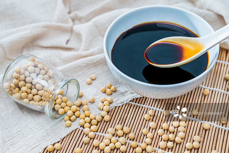 撒在竹席上的许多大豆和一碗酱油图片素材