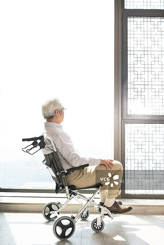 老年男子坐在轮椅上看向窗外图片素材