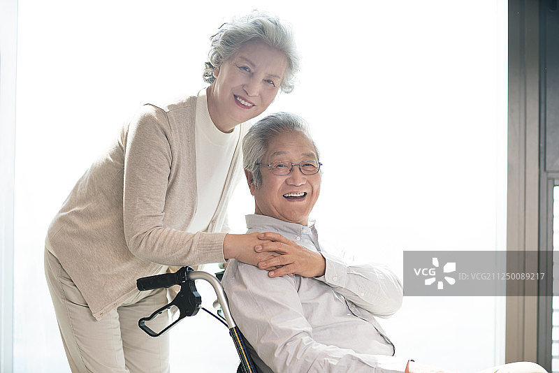 老年女子照顾坐轮椅的丈夫图片素材