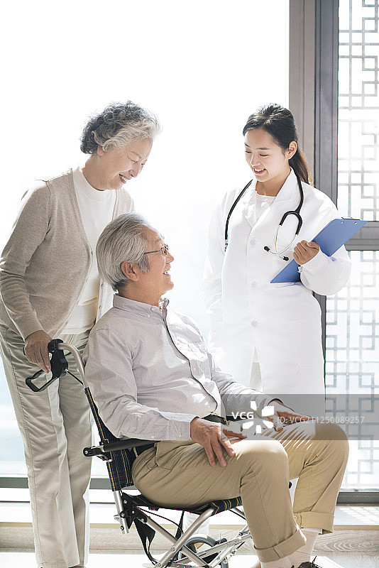 护工与坐轮椅的老年夫妇交谈图片素材