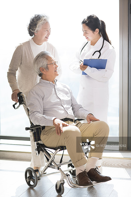 护工与坐轮椅的老年夫妇交谈图片素材