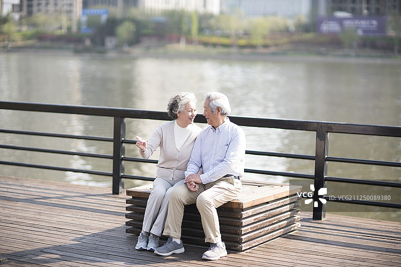 快乐的老年夫妇坐在河边休息图片素材