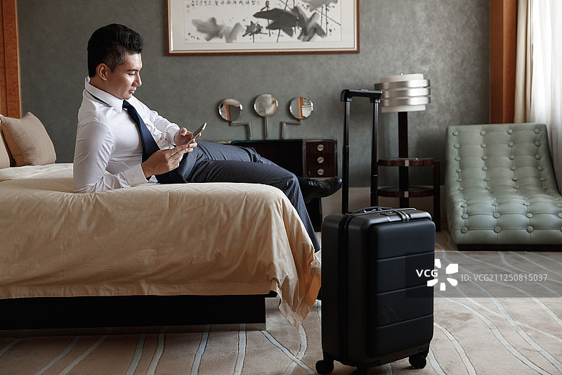 青年男士躺在床上看手机图片素材