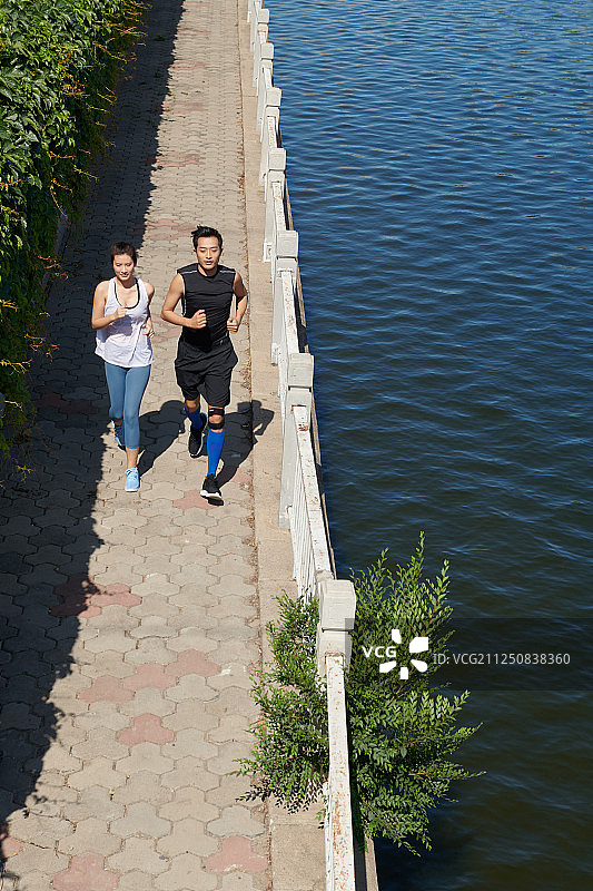 两个年轻人在城市运河跑步图片素材