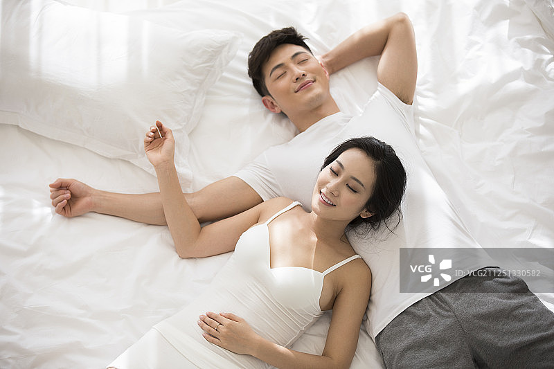 快乐的年轻情侣躺在床上睡觉图片素材