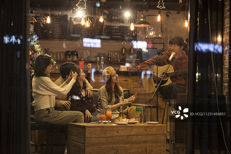 五个青年男女在酒吧弹吉他唱歌喝酒一起欢度圣诞节平安夜图片素材