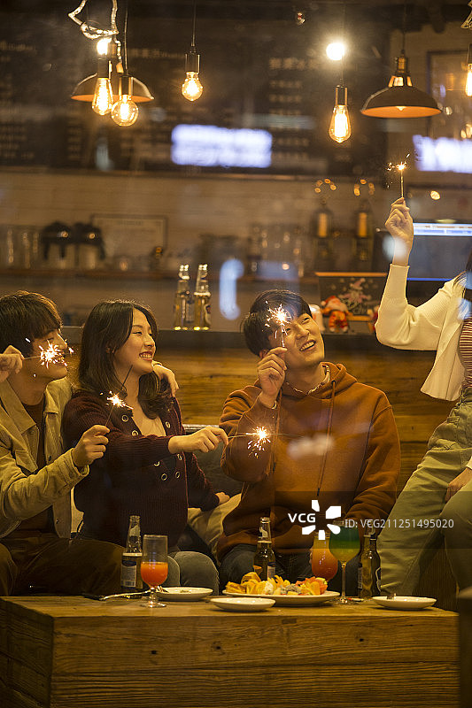 四个青年男女一起在酒吧聚会嬉戏放烟花欢度圣诞节图片素材