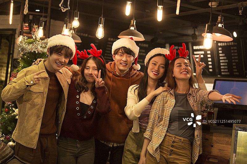 五个青年男女在咖啡厅搂在一起拍照玩耍嬉戏庆祝平安夜和圣诞节图片素材