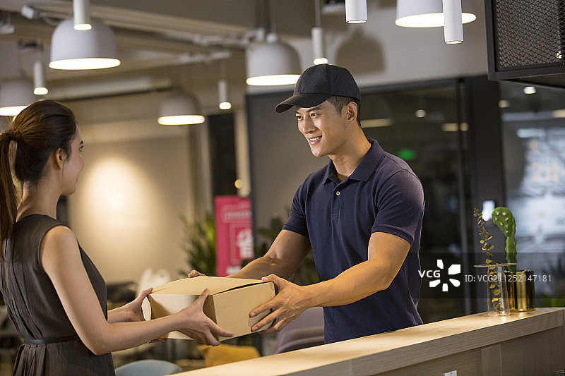 青年男快递员递给青年女子快递包裹图片素材