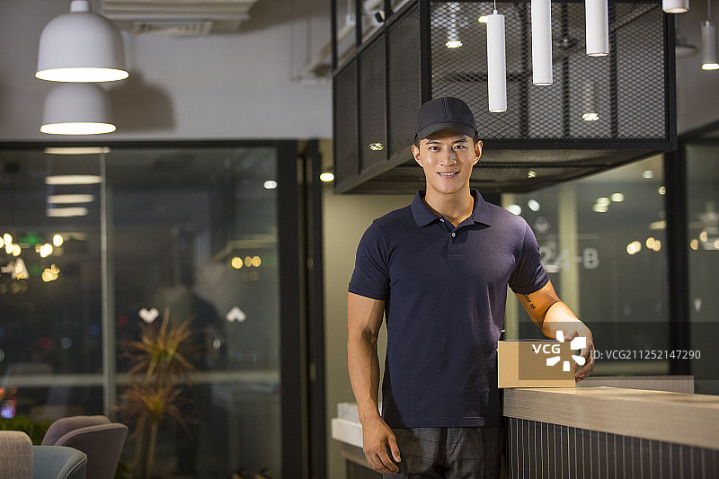 青年男快递员拿着快递包裹图片素材