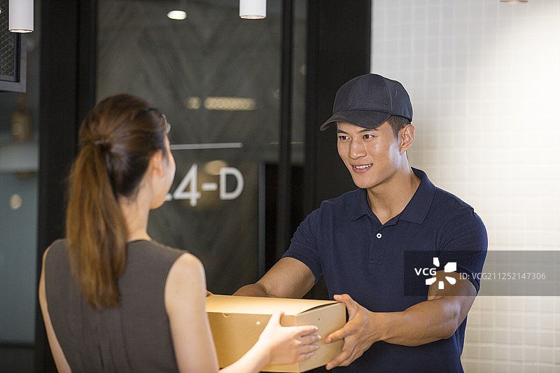 公司前台青年女子和青年男快递员图片素材