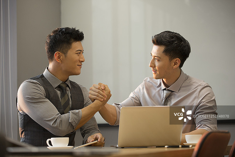 商务青年男子使用笔记本电脑在公司会议室讨论工作握手庆祝达成共识图片素材