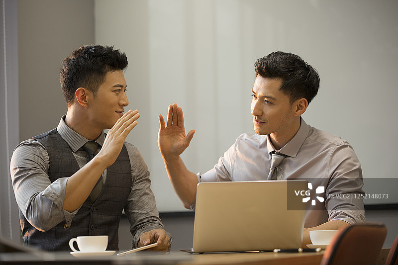 商务青年男子使用笔记本电脑在公司会议室讨论工作击掌庆祝达成共识图片素材