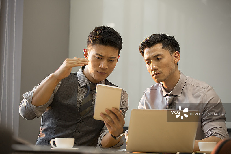 商务青年男子使用笔记本电脑在公司会议室讨论工作图片素材