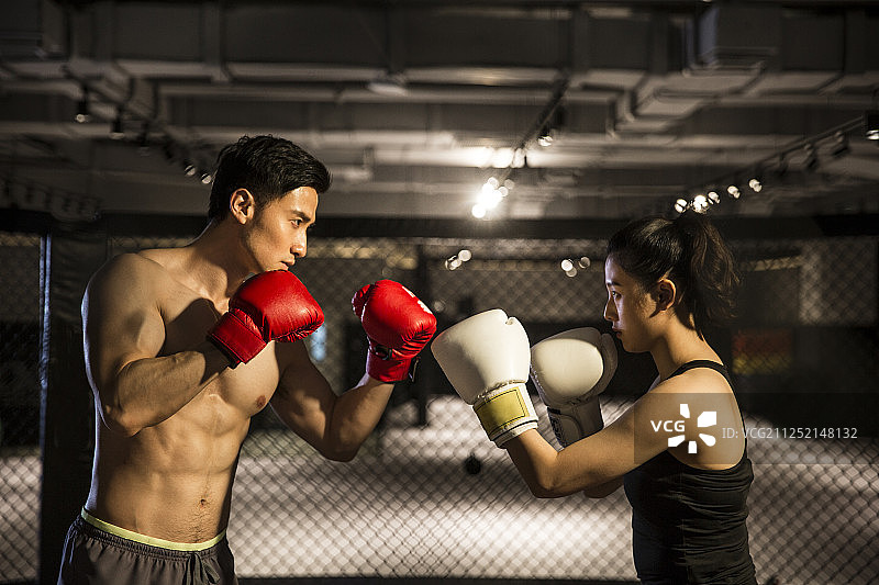青年男拳击手和青年女拳击手打拳击对抗比赛在拳击台图片素材