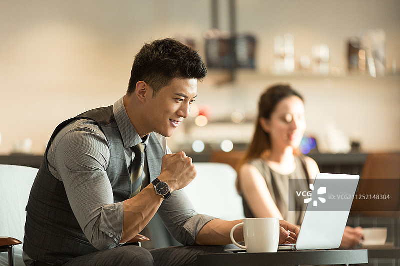 商务青年男子在咖啡馆喝咖啡使用笔记本电脑欢呼加油图片素材
