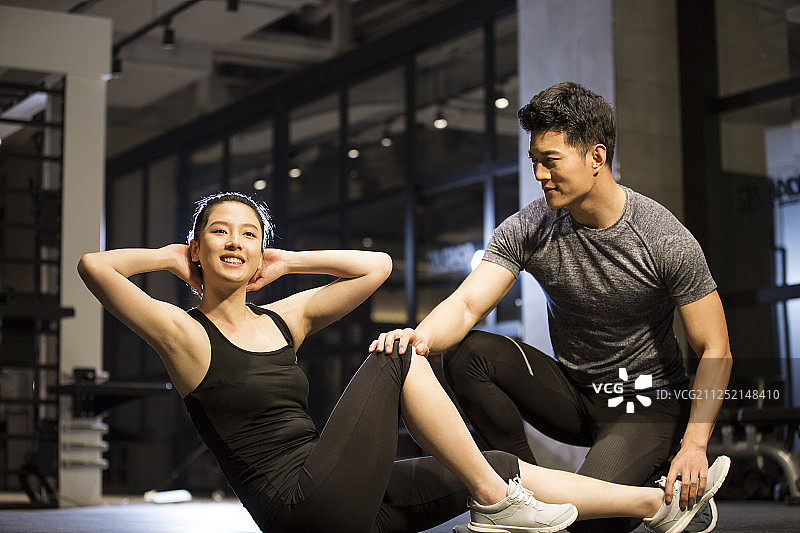 青年男子和青年女子在健身房做仰卧起坐运动图片素材