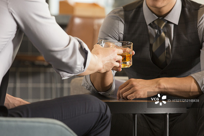 两个商务青年男子在酒店酒吧干杯喝酒特写图片素材