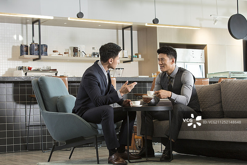 两个成功商务青年男子在酒店咖啡馆喝咖啡沟通讨论工作图片素材