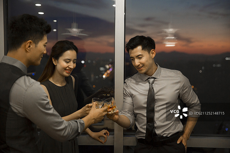 三个青年商务男女站在会议室窗前喝酒干杯庆祝成功图片素材