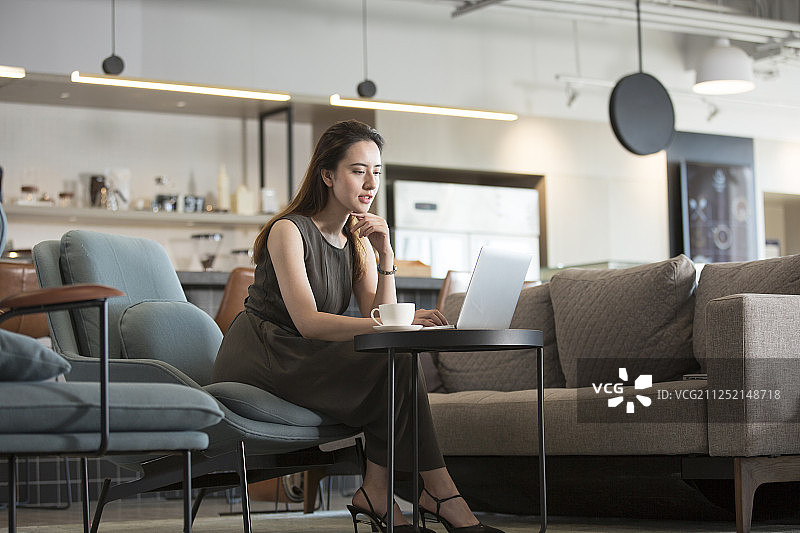 一个成功青年女商务人士在酒店咖啡馆喝咖啡使用笔记本电脑工作图片素材