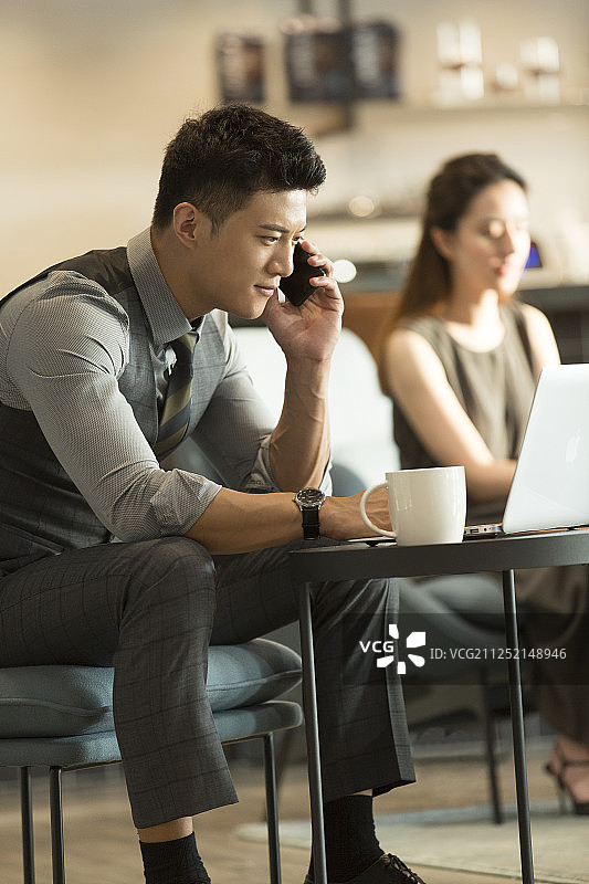 青年商务男子在咖啡馆喝咖啡打电话使用笔记本电脑工作图片素材