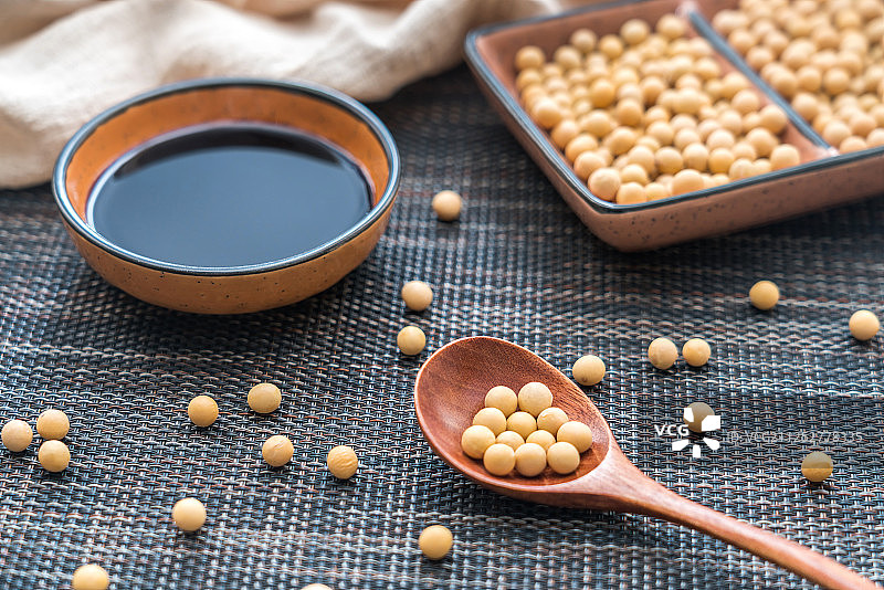 撒在竹席上的许多大豆和一碗酱油图片素材