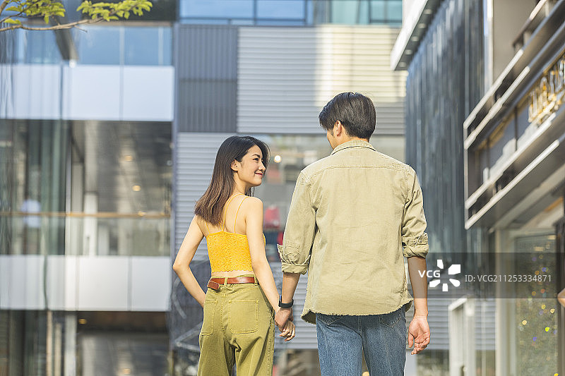 甜蜜情侣在户外商业街手牵手浪漫逛街旅行图片素材