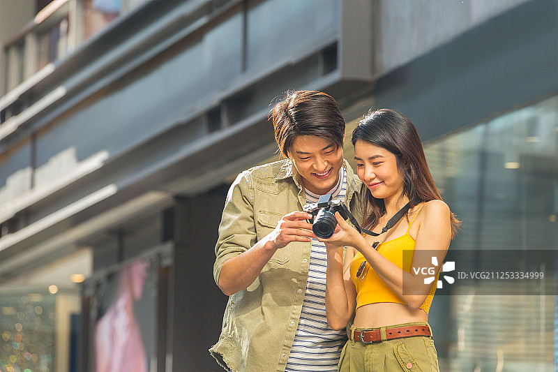 甜蜜情侣在户外步行街逛街旅游拍照看相机照片图片素材