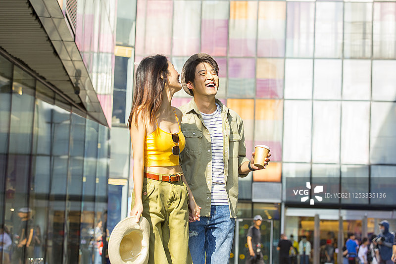 青年情侣在户外商业街手牵手拿着咖啡杯逛街旅行图片素材