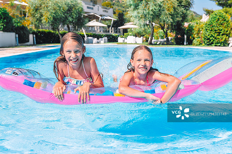 在户外游泳池里玩耍的可爱小姐妹图片素材