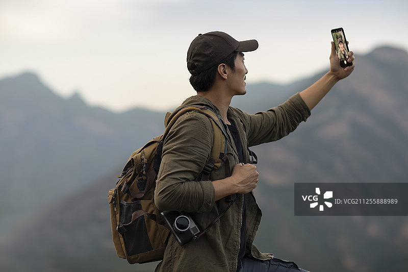 年轻男士在户外使用手机自拍图片素材