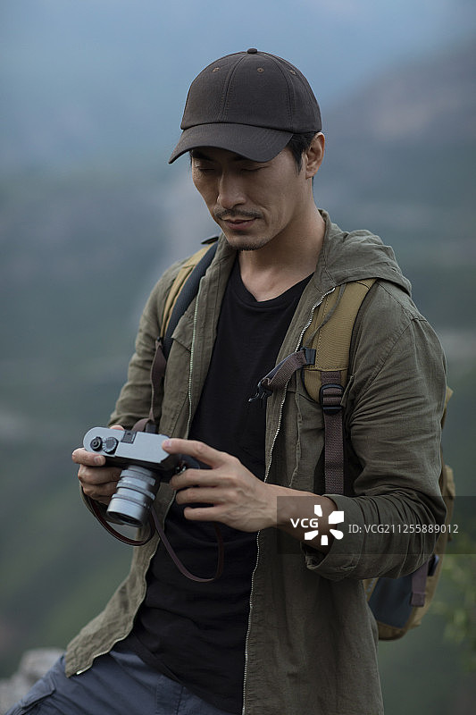 年轻男士在户外使用相机拍照图片素材