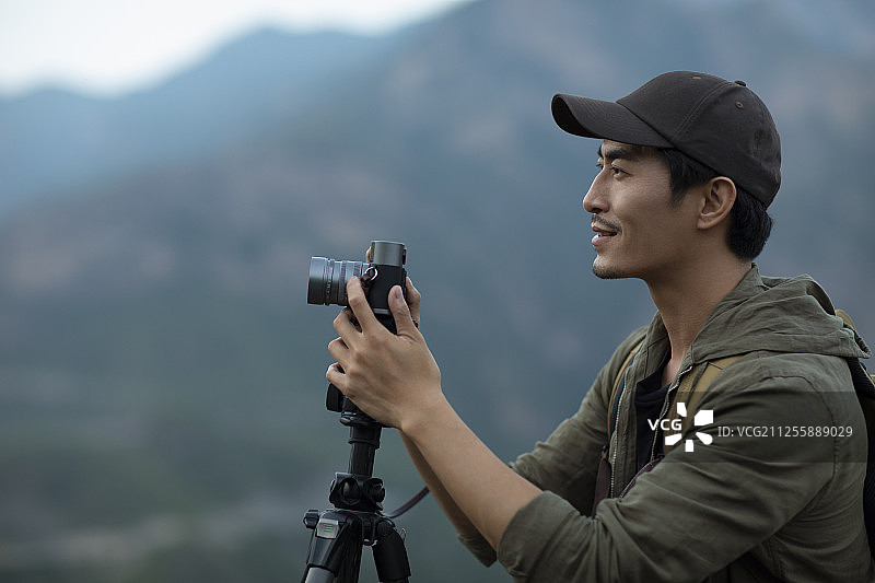 年轻男士在户外使用相机拍照图片素材