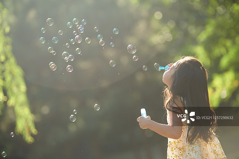小孩在公园做吹泡泡游戏图片素材